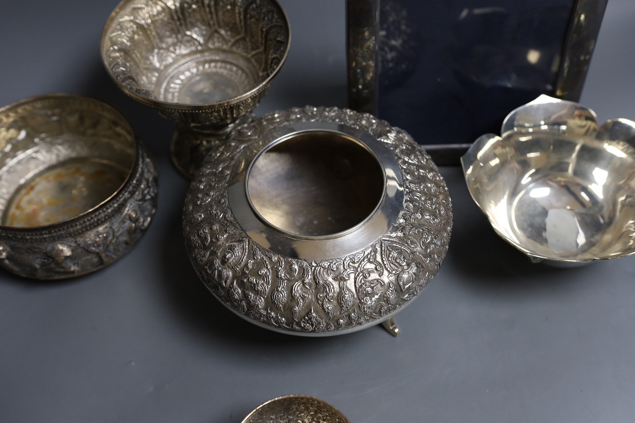 Six assorted embossed Thai white metal bowls, largest 18cm diam., and a silver photograph frame